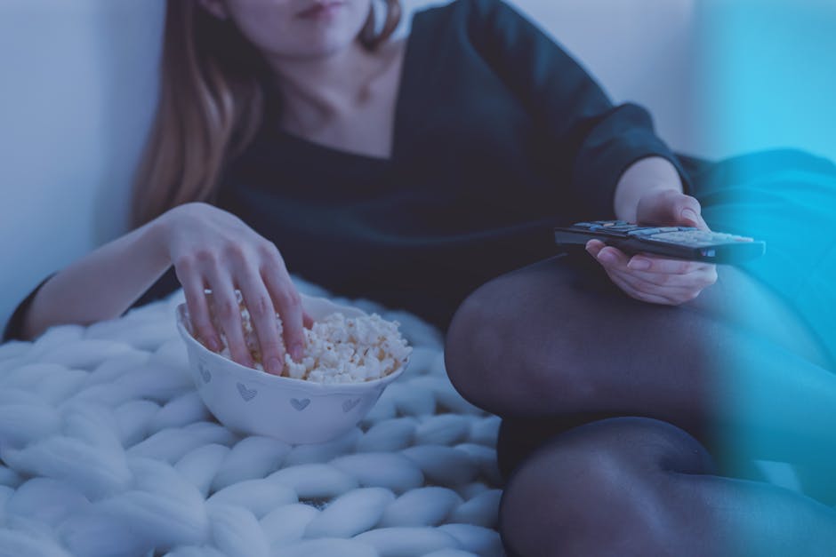 Cozy evening scene with woman enjoying popcorn and watching TV